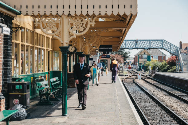 chef de train marchant sur la gare de sheringham avec un sandwich à la main, norfolk, royaume-uni. - north norfolk photos et images de collection