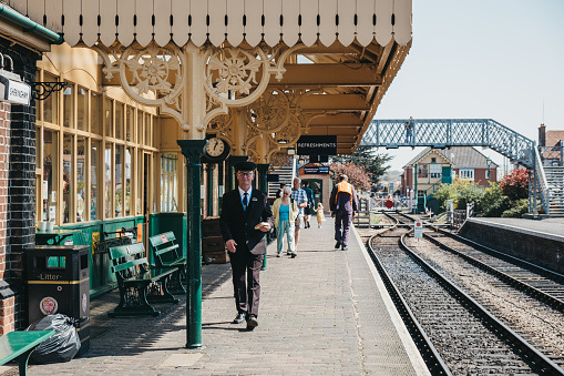 Sheringham, UK - April 21, 2019: Conductor walking on Sheringham train station with a sandwich in hand. Sheringham is an English seaside town within the county of Norfolk, UK.