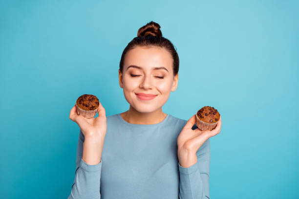 nahe foto schön sie ihre dame beraten kauf käufer versuchen, neue leckeren leckeren leckeren leckeren kakao farbe muffins verträumt die augen schöne geruch tragen lässige pullover isoliert blauen hellen hintergrund - close up cookie gourmet food stock-fotos und bilder