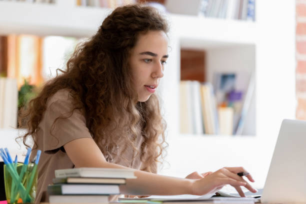 istock Serious student girl studying using laptop sitting at classroom desk 1146488453