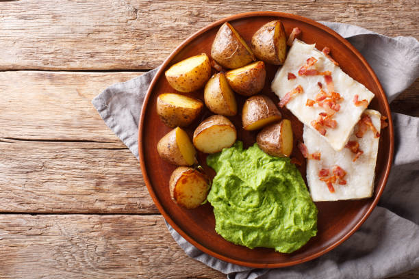 人気のスカンジナビア料理のタラは、エンドウのピューレ、焼きたてのジャガイモ、ベーコンのクローズアップをプレートに lutefisk ています。水平トップビュー - stockfish ストックフォトと画像