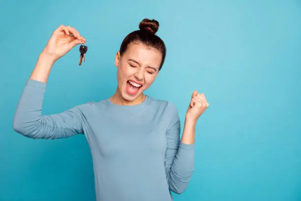 Photo of Portrait of delighted lady luck lucky triumph raise fists close eyes content rejoice scream shout yeah mover move in settlement loan beautiful bun trendy stylish sweater isolated on blue background