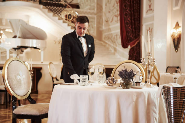 istock Everything must be perfect. Process of preparing place for special visitors. Waiter in classical wear works on the servering 1146490756