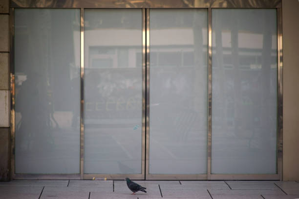 A modern sliding glass door of a shopping mall with shiny metal frame.\