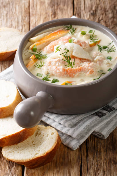 deliziosa zuppa di pesce cremoso con merluzzo e salmone da vicino in una ciotola servita con pane fresco. verticale - main course salmon meal course foto e immagini stock