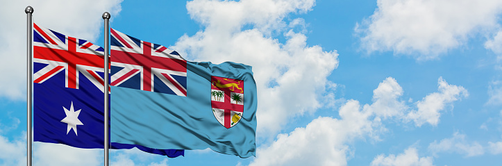 Australia and Fiji flag waving in the wind against white cloudy blue sky together. Diplomacy concept, international relations.