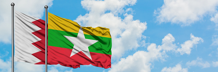 Bahrain and Myanmar flag waving in the wind against white cloudy blue sky together. Diplomacy concept, international relations.