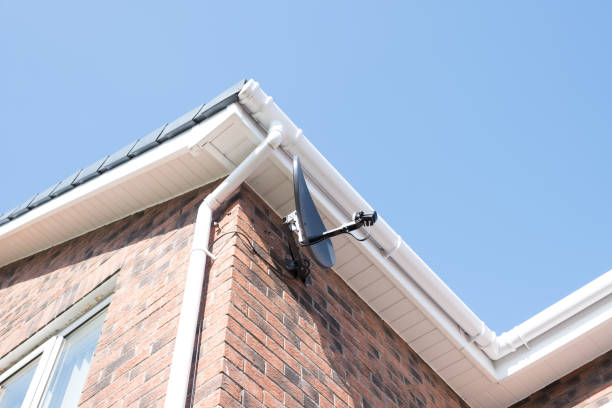 Satellite Dish Newly Installed on Gable End Wall of Modern Dwelling A newly fitted Satellite Dish at the side of a residential building. A good image for a engineer, Installer, or similar trades. installing tv stock pictures, royalty-free photos & images