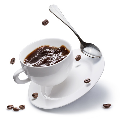 Coffee cup, coffee beans and spoon flying over a white plate on white background.