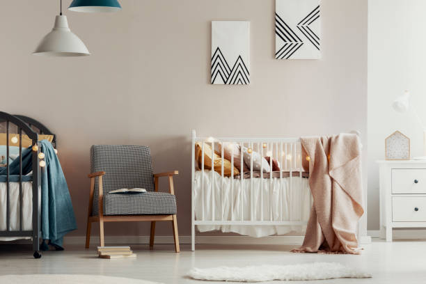 Fashionable retro armchair between two wooden cribs in cute twins nursery Fashionable retro armchair between two wooden cribs in cute twins nursery beige bedroom stock pictures, royalty-free photos & images