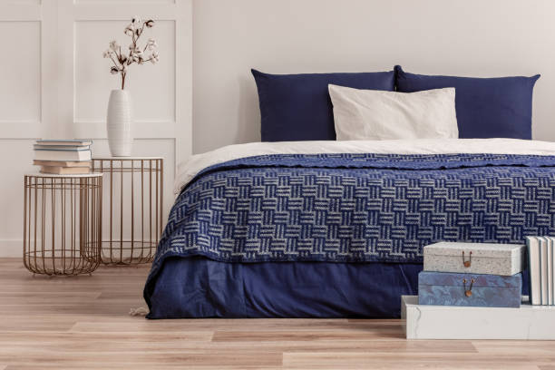 istock Flowers in vase on bedside table next to king size bed with navy blue bedding 1146501563
