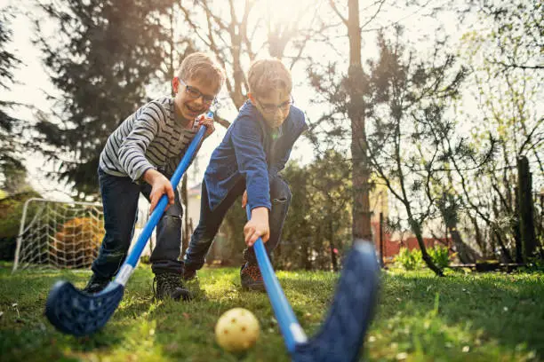 Little boys playing floorball in the garden. 
Nikon D850