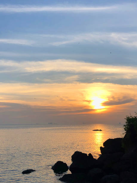 immagine della splendida spiaggia indiana di goa con cielo al tramonto rosa arancione, mare, nuvole e riflessi della costa dell'alba / tramonto nella foto della spiaggia di dona paula, goa, india meridionale, con sagome di rocce, sabbia, increspature che l - sunset vacations orange glowing foto e immagini stock