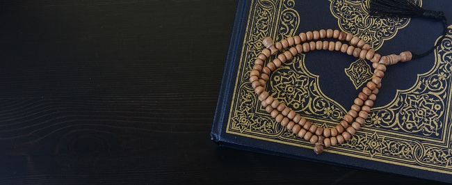 Close-up al-Quran y perlas con fondo de madera de mesa negro superior photo
