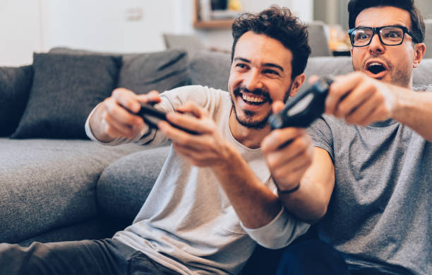 Excited friends playing video games Excited friends playing video games at home handheld video game stock pictures, royalty-free photos & images