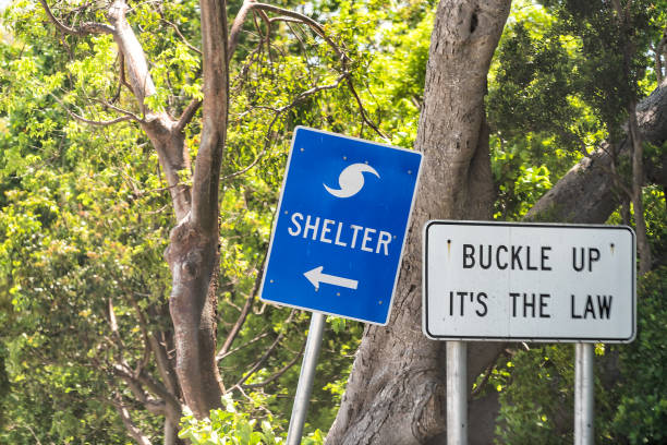 Hurricane evacuation shelter blue sign on road and seat belt buckle up it's the law text with arrow direction in Naples, Florida during day Hurricane evacuation shelter blue sign on road and seat belt buckle up it's the law text with arrow direction in Naples, Florida during day collier county stock pictures, royalty-free photos & images