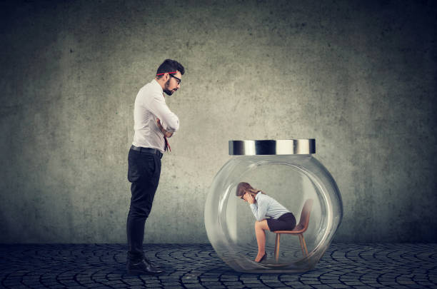 Authoritarian boss businessman looking at a glass jar with captured woman inside Authoritarian angry boss businessman looking at a glass jar with captured woman inside exploitation stock pictures, royalty-free photos & images