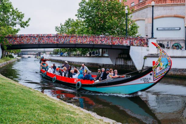 Aveiro, Portugal - April 29, 2019: Traditional boat, Moliceiro, transporting tourists passing under bridge covered in confetti on canal at Aveiro, Portugal