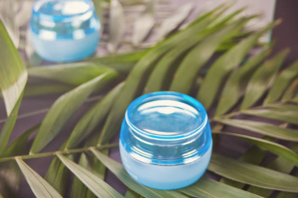 istock Blue container with facial or body cream on the palm leaf 1146514528