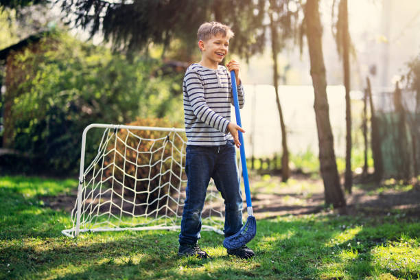 маленький мальчик, играющий в полбол на заднем дворе - field hockey ball individual sports sports and fitness стоковые фото и изображения