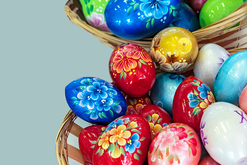 Colorful Easter eggs in a wicker basket on a gray background.
