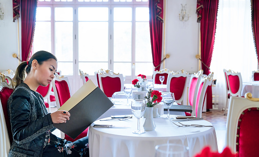 Woman looking at food menu on dining table in luxury restaurant