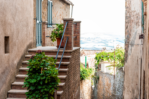 Montalcino, Italy historic medieval town village in Tuscany with nobody and view of rolling hills and mountains between buildings, steps to garden home