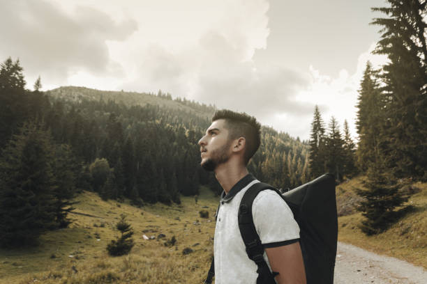 istock young hiker with backpack looking up to sky in front of fir trees 1146532722