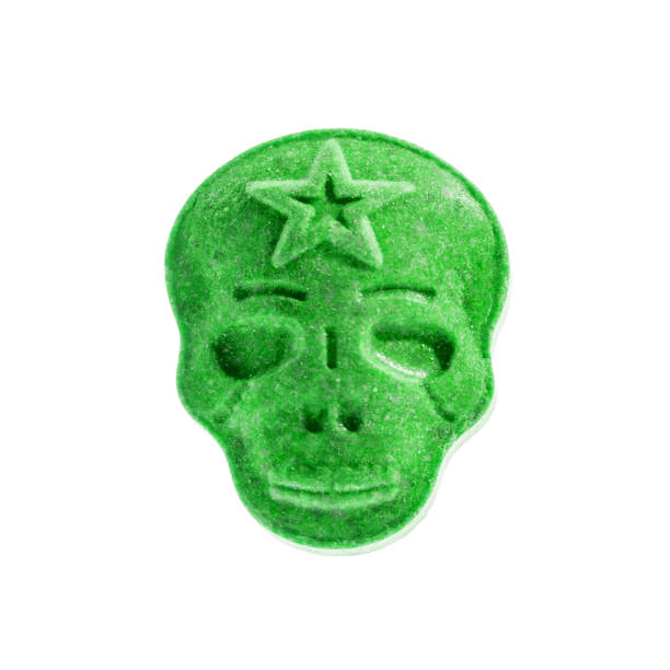 one green xtc, ecstasy, mdma, amphetamine or medication pill shaped like a skull isolated on a white background. - ecstasy imagens e fotografias de stock