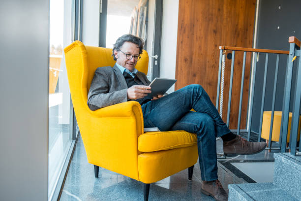 istock Mature caucasian man sitting in an armchair and using a digital tablet 1146533932