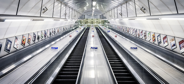 17 Nov 2015 - London, United Kingdom. Looking up at symmetrical stainless steel escalators leading out from London Underground tube station.