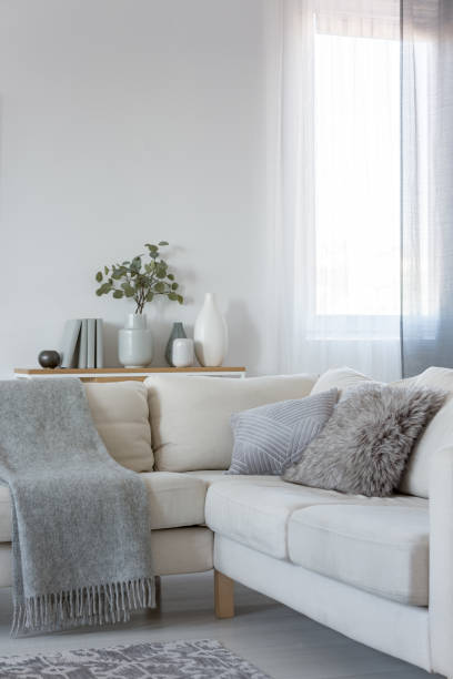 istock Vertical view of corner sofa with pillows and blanket, copy space on empty white wall 1146540917
