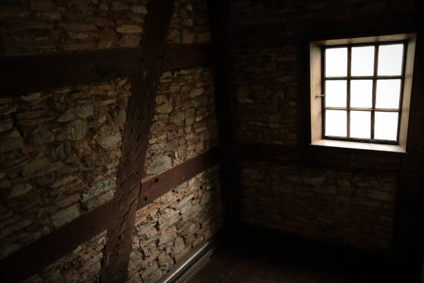 Sunlight shines into dark empty cellar through lonely window stock photo