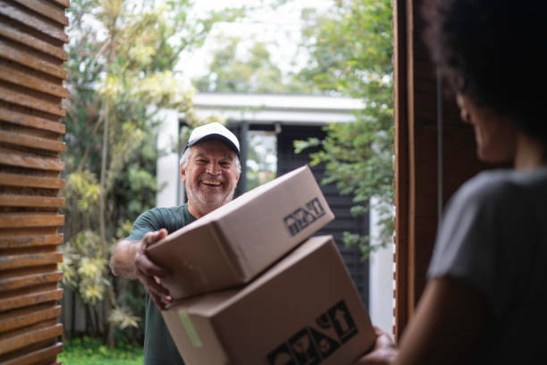 若い女性に箱を届ける宅配便 - postal worker ストックフォトと画像