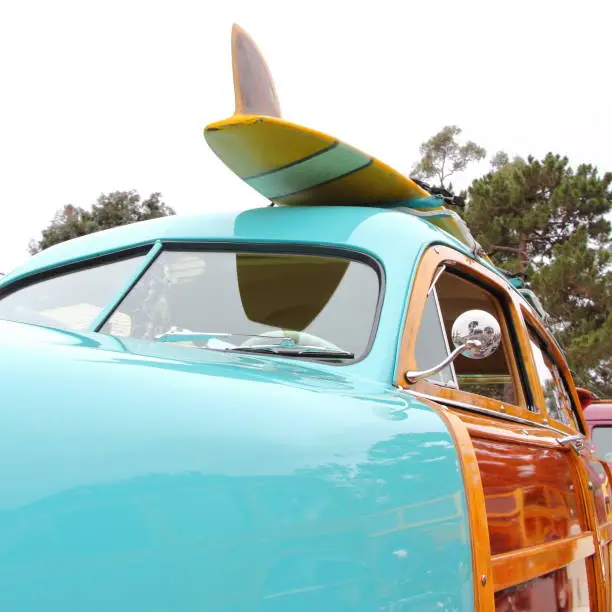 A surfboard mounted on top of a woodie stationwagon.