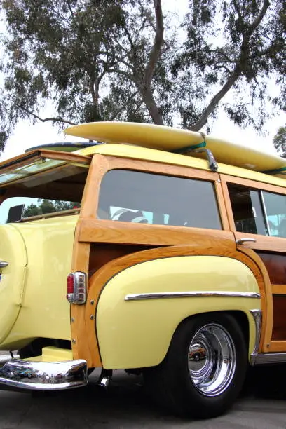 A surfboard mounted on top of a woodie stationwagon.