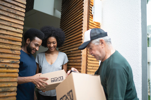 Courier delivering boxes to a young couple