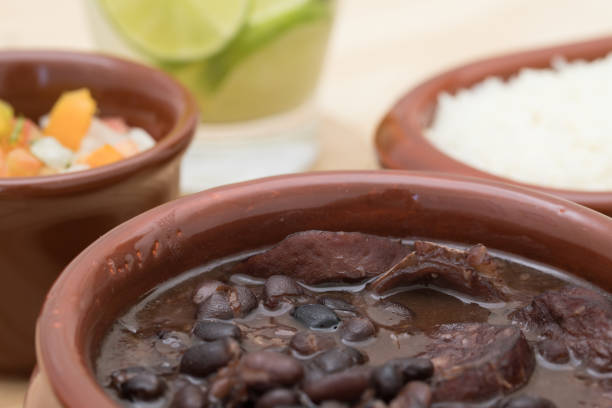 istock Brazilian Feijoada (black bean meal), side dishes and caipirinha cocktail on background 1146547088