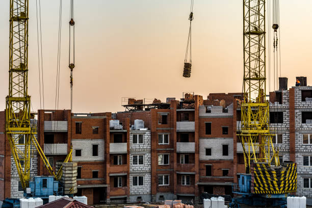 Building crane at the background of a multi-storey building under construction stock photo