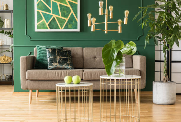 Elegant green and gold living room with comfortable brown sofa, coffee tables and golden chandelier Elegant green and gold living room with comfortable brown sofa, coffee tables and golden chandelier parquet floor photos stock pictures, royalty-free photos & images