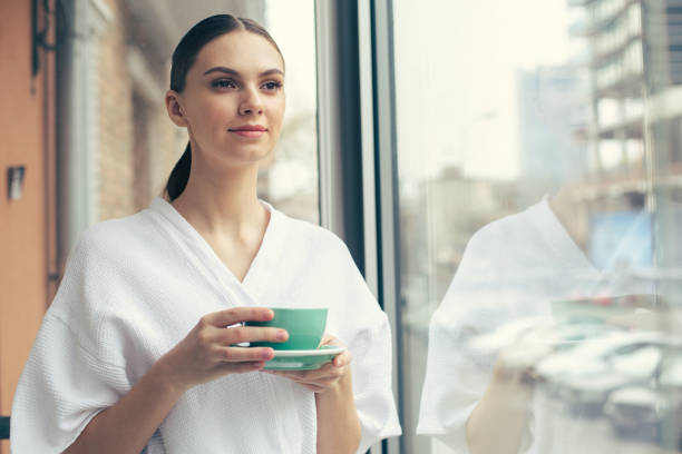 istock Beautiful woman enjoying her tea while standing near the window 1146548253