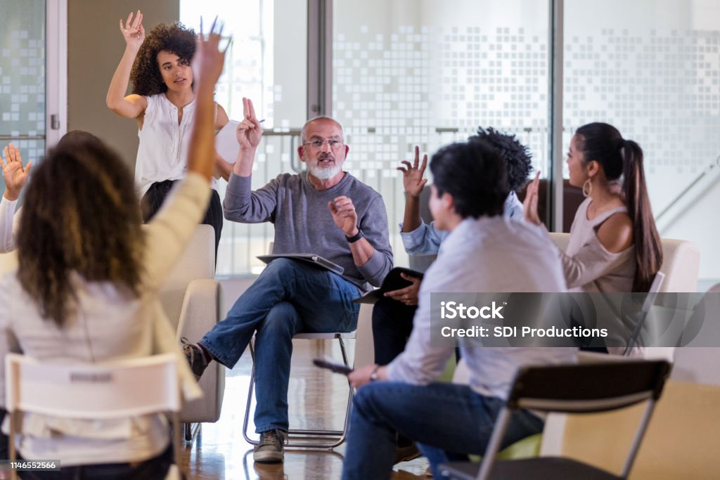 Group of neighbors take a vote during HOA meeting Mature male HOA president leads his neighbors in a vote during an HOA meeting. Meeting Stock Photo