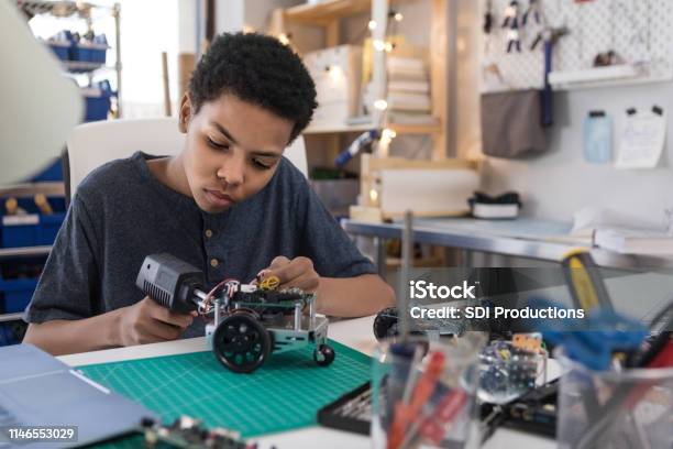 Teen Boy Solders Wires To Build Robot Stock Photo - Download Image Now - Child, Robot, Technology