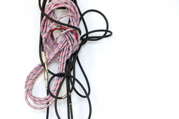 Untidy musical instrument cables. Tangled guitar leads hanging on a music practice room wall. Musician related image with copy space.