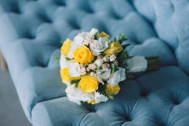 A beautiful wedding bouquet with white and yellow roses on a blue sofa. Wedding photography, copy space, poster. stock photo