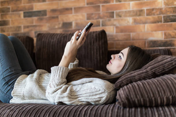 istock Young woman reading on her mobile phone with smile in a close up profile view on a sofa 1146561101