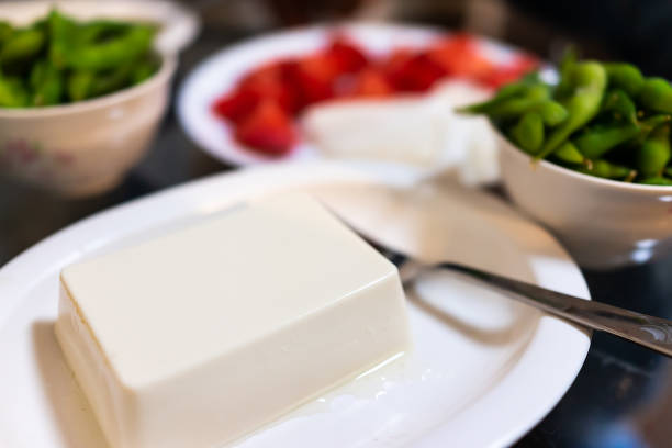 assiette de tofu ordinaire bouilli ou froid dans un restaurant ou une maison avec une collation de plat végétal de edamame bouilli et une fourchette - 13412 photos et images de collection