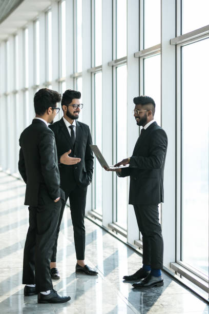 istock Three asian corporate executives standing in front of windows discussing business using laptop computer. 1146565850