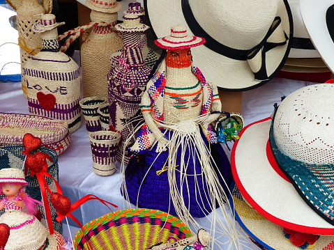 Various wicker souvenirs - baskets, dolls, bottles, vases, hats and more - made from toquilla straw, vegetable fiber, and painted with various colors at the artisan market in Cuenca, Ecuador