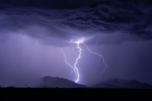 A lightning bolt strikes a mountain and lights up the night sky during a storm.